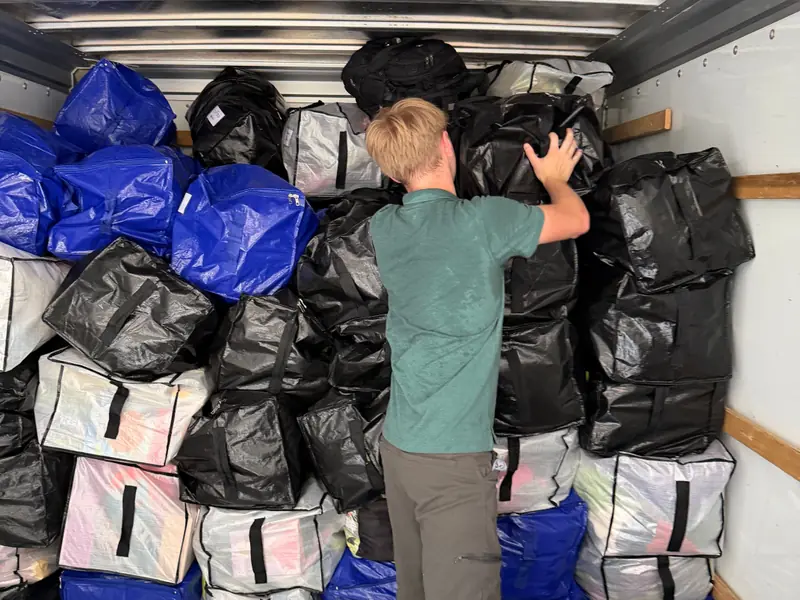 One of our movers stacking moving bags into a tight wall inside a rental truck.