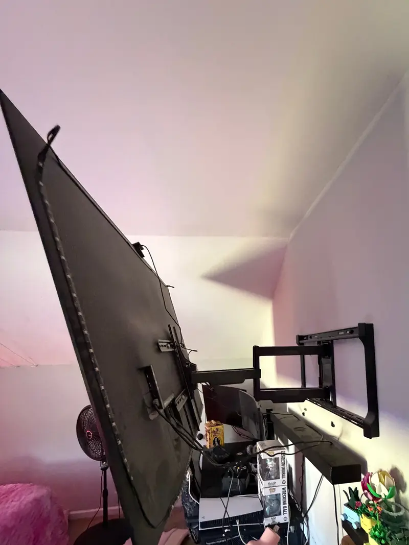 A large flat-screen TV swung out from the wall on an articulating mount, in a room with a sloped ceiling.